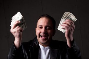 excited man holds up cash after winning a sweepstakes 
