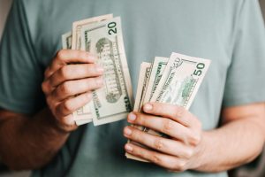 Man holding wads of cash in both hands.